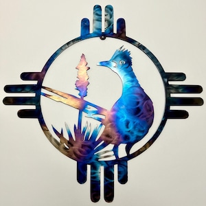 May include: Metal wall art featuring a roadrunner bird within a circular design, set against a white background. The roadrunner and surrounding elements are rendered in shades of blue, purple, and bronze. The design includes a stylized sun and plant life.