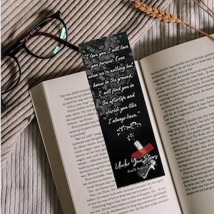 Puede incluir: Marcapáginas negro con cita romántica, diseño floral e ilustración de pistola, sobre un libro abierto. También se ven unas gafas.