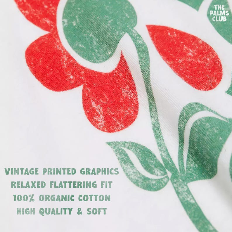 May include: White t-shirt with a green and red floral print. The text "THE PALMS CLUB" is printed in the top right corner. The text "VINTAGE PRINTED GRAPHICS", "RELAXED FLATTERING FIT", "100% ORGANIC COTTON", and "HIGH QUALITY & SOFT" is printed in green at the bottom of the shirt.