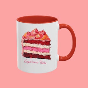 May include: White ceramic mug with a red rim and handle. The mug features a colorful painting of a slice of cake with the text "Sagittarius Cake" underneath.