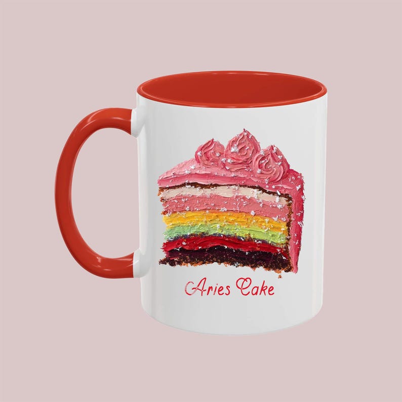 May include: White ceramic mug with a red rim and handle. The mug features a colorful cake slice with pink frosting and the text "Aries Cake".