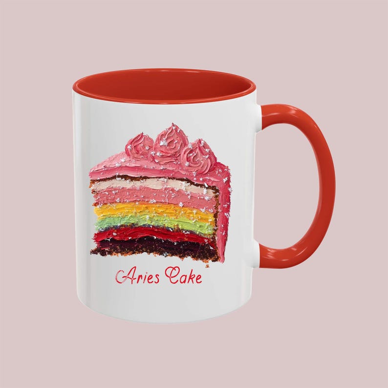 May include: White ceramic mug with a red rim and handle. The mug features a colorful cake with pink frosting and the text "Aries Cake".