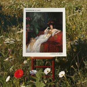 May include: A framed print of a painting depicting a woman in a white dress sitting on a red couch with a dog. The painting is titled "Persephone (c.1443)" and the text "Goddess of Spring" is at the bottom of the print. The print is sitting on a wooden stool in a field of wildflowers.