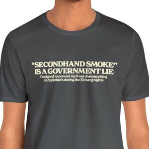 May include: A dark gray t-shirt with a white graphic print that reads "SECONDHAND SMOKE" IS A GOVERNMENT LIE Designed to prevent me from chainsmoking at Applebee's during the SI marg nights"