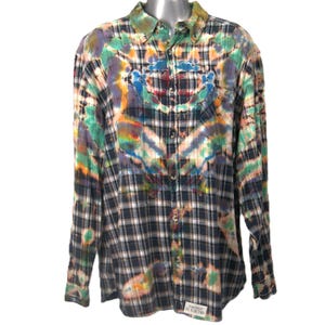 May include: A long-sleeved plaid shirt with a tie-dye pattern in shades of blue, green, orange, and pink. The shirt has a button-down collar and a button-up front.