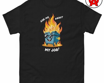 Puede incluir: Una camiseta negra de manga corta con un gráfico de un contenedor de basura azul con gafas de sol y envuelto en llamas. El texto sobre y debajo del contenedor dice "ASK ME ABOUT MY JOB!" y está centrado en la parte frontal de la prenda.