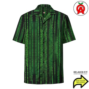 Peut inclure: Chemise à manches courtes verte et noire avec un motif répété de lignes verticales de symboles. La chemise a une coupe décontractée. Le texte "RELAXED FIT" et "SIZE GUIDE INCLUDED" est inclus.