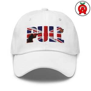 Könnte beinhalten: Weiße Baseballkappe mit dem Wort "PULL", das in einem Design gestickt ist, das die Flagge des Union Jack enthält. Der Buchstabe "P" zeigt eine Silhouette einer Person, die mit einem Gewehr zielt. Die Kappe hat einen gebogenen Schirm.