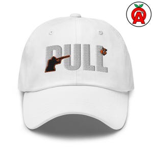 May include: White baseball cap with the word "PULL" in gray, featuring an orange and black silhouette of a person aiming a shotgun. The cap also has an orange and black target graphic.