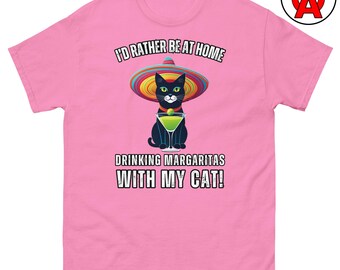 May include: Pink t-shirt with a graphic of a black cat wearing a sombrero and holding a margarita. Text reads "I'D RATHER BE AT HOME DRINKING MARGARITAS WITH MY CAT!"