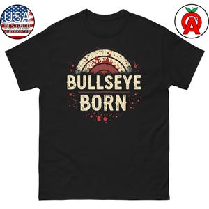 May include: Black t-shirt with a vintage-style graphic of a bullseye target with red and white accents. The text "Bullseye Born" is printed in white below the target.