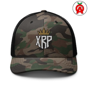 May include: Camouflage trucker hat with a black mesh back and a curved peak. The front of the hat features an embroidered white design of the letters "XRP" beneath a gold crown. The hat is a mix of green, brown, and black.