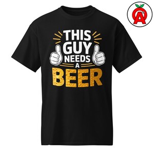 May include: Black t-shirt with the text "THIS GUY NEEDS A BEER" in white and gold. The design includes two thumbs-up gestures and radiating lines. A fun, casual tee for beer lovers.