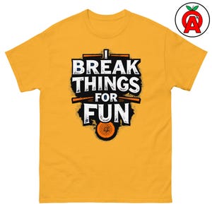 Könnte beinhalten: Gelbes T-Shirt mit einem grafischen Aufdruck, der "I Break Things For Fun" lautet. Die Grafik ist im Used-Look gehalten und hat ein kreisförmiges Design in der Mitte.