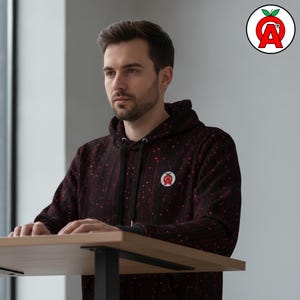 A male software engineer in his late 20s wearing the hoodie while working at a standing desk showing off Binary Code AOP Hoodie, Computer Programming Unisex Top, Digital Matrix Graphic Pullover, Hacker Aesthetic Soft Sweater