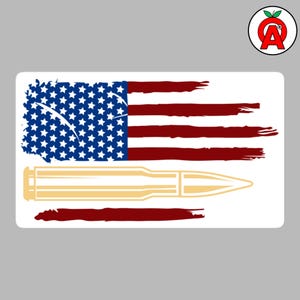 May include: A rectangular sticker featuring a stylized American flag design. The flag's stars are blue, and the stripes are red. A gold-coloured bullet is positioned below the flag.
