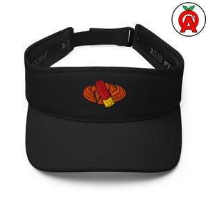 May include: Black visor with an embroidered design of a red and yellow shotgun shell inside an orange emblem. The visor has the text "110 FIT" on the side.