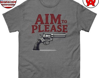 以下が含まれることがあります： 赤い文字で「AIM TO PLEASE」と書かれたグレーのTシャツ。テキストの下に銀色のリボルバーが描かれています。