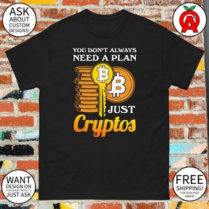 May include: Black t-shirt with a yellow and orange graphic design. The graphic features a stack of gold coins with a key and the text "You don't always need a plan, just cryptos".