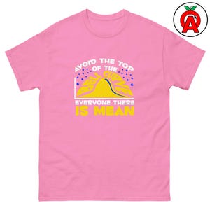 Puede incluir: Una camiseta rosa con el texto "AVOID THE TOP OF THE CURVE, EVERYONE THERE IS MEAN" en blanco y amarillo. El gráfico incluye una curva de campana amarilla y puntos azules.