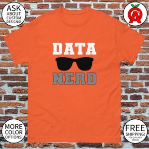 Könnte beinhalten: Orangefarbenes T-Shirt mit den Worten "DATA NERD" in Weiß und Grau sowie einer schwarzen Sonnenbrille. Das T-Shirt hat eine klassische Passform und besteht aus einem weichen Material. Ein tolles Geschenk für Datenbegeisterte.