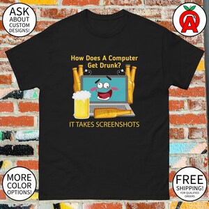 May include: Black t-shirt with a humorous graphic. The design features a cartoon laptop with a smiling face, surrounded by beer bottles and a glass of beer. Text reads: "How Does A Computer Get Drunk? IT TAKES SCREENSHOTS."