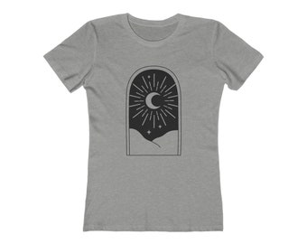May include: A gray t-shirt featuring a black graphic of a crescent moon surrounded by radiating lines, stars, and a landscape scene. The design is framed within an arched shape. The shirt has short sleeves and a crew neck.