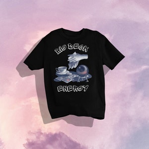 May include: Black t-shirt with a graphic design of a hand holding a teacup, a crystal ball, and playing cards. The text "BIG DECK ENERGY" is printed on the shirt.