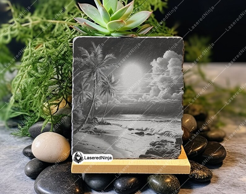 May include: A black slate coaster with a laser-engraved image of palm trees on a beach with a sunset and clouds. The coaster is on a wooden stand.