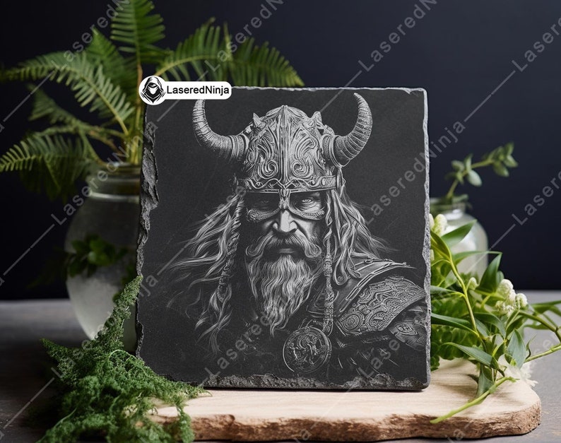 May include: Black and white engraved image of a Viking warrior with a horned helmet and long beard on a black slate coaster.