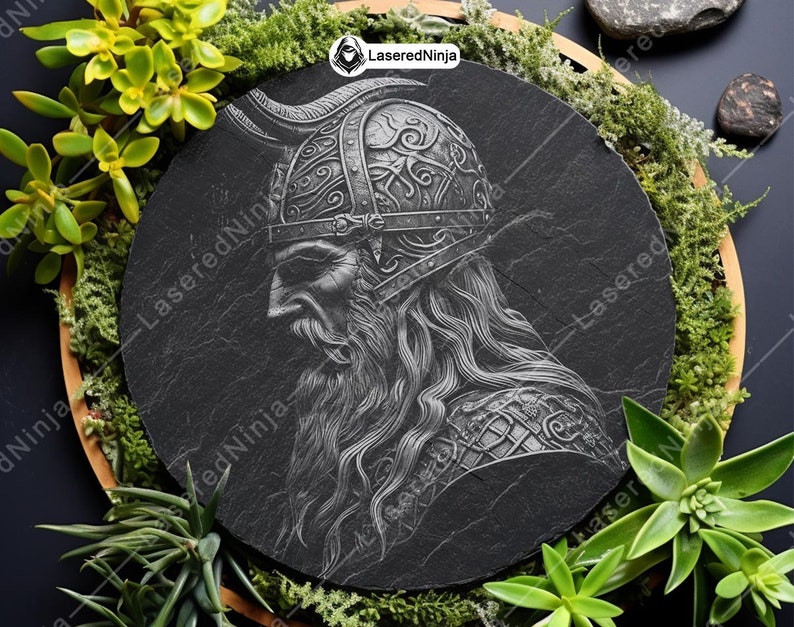 May include: A black and white engraved image of a Viking warrior with a horned helmet and a long beard. The image is on a round black slate plaque.