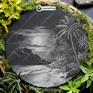 May include: A black slate round coaster with a laser engraved design of a tropical beach scene with palm trees, a moon, and mountains. The coaster is surrounded by green plants.