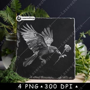 May include: A black square slate features an engraved image of a raven in flight, holding a rose in its beak. The raven's wings are spread, and the rose is detailed. The slate has a natural, textured edge.