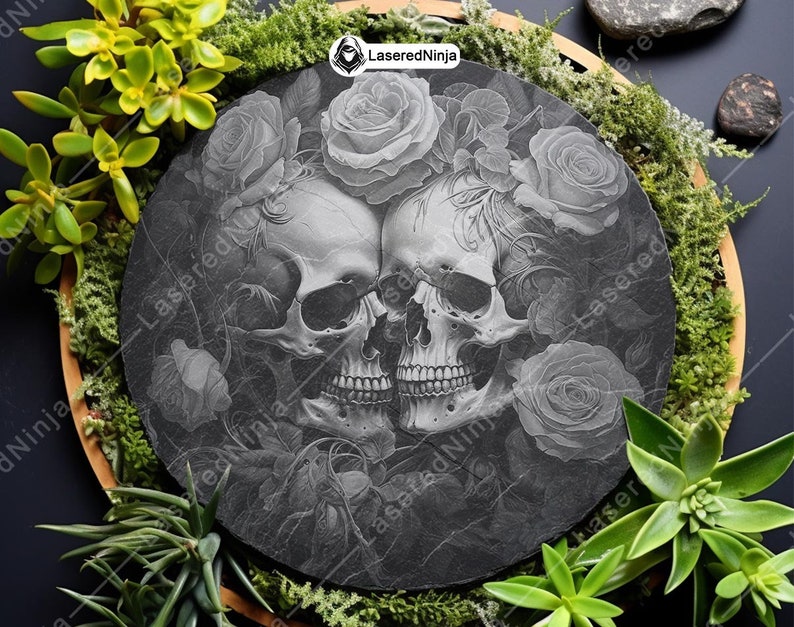 May include: Black and white engraved image of two skulls intertwined with roses on a round black slate coaster. The image is in a gothic style.