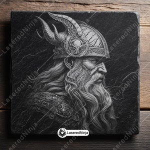 May include: A black and white illustration of a Viking warrior with a long beard and a horned helmet. The image is engraved on a black slate coaster.
