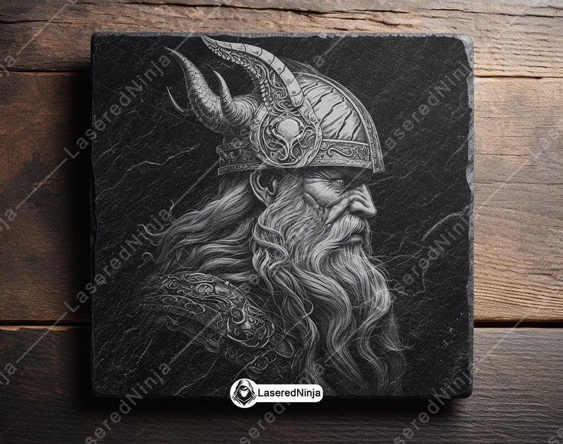 May include: A black and white illustration of a Viking warrior with a long beard and a horned helmet. The image is engraved on a black slate coaster.