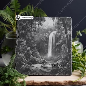 May include: A black and white engraved slate coaster featuring a detailed illustration of a waterfall in a lush jungle setting.