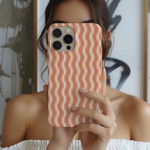 May include: A smartphone case featuring a repeating pattern of vertical wavy lines in alternating shades of terracotta orange and cream. The case has a rectangular cutout for the camera lens array on the upper left corner.