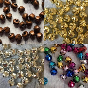 May include: Assortment of jingle bells in various colours, including silver, gold, copper, and rainbow. The bells are small and have a classic bell shape.