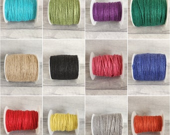 May include: Twelve spools of twine in various colors, including teal, green, purple, black, natural, red, yellow, gray, and orange. The spools are all the same size and are arranged in a grid pattern.
