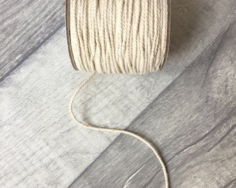 May include: A spool of natural cotton twine, wound tightly and ready to be used for crafting, wrapping, or macrame projects.