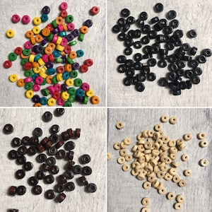 May include: Assortment of wooden beads in various colours, including black, brown, natural, and multi-coloured. The beads are round with a hole in the centre.