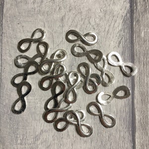 May include: A pile of silver infinity symbol charms. The charms are small and delicate, and they are perfect for adding a touch of whimsy to jewellery or crafts.
