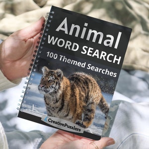 May include: A black and white spiral bound book with the title "Animal Word Search" and the subtitle "100 Themed Searches". The cover features a photo of a tiger cub running through the snow. The book is published by CreativePuzzlers.