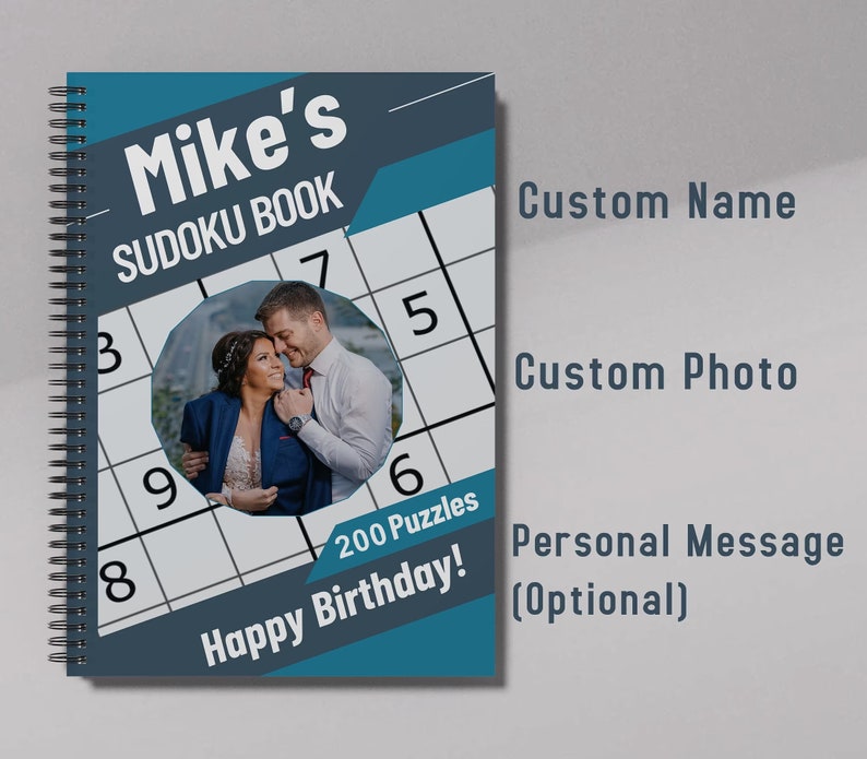 May include: A blue and gray personalized Sudoku book with a photo of a couple, the text "Mike's Sudoku Book", and the message "Happy Birthday! 200 Puzzles".