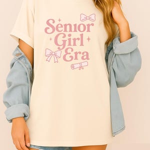 Camiseta de la era de las chicas mayores • Camiseta de graduación de la clase de 2026 • Camiseta violeta de colores cómodos • Lindo regalo para estudiantes de último año • Camiseta de graduación con lazo para el diploma para ella