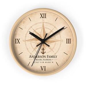 Op de afbeelding: Een ronde wandklok met een lichthouten frame en een beige wijzerplaat in vintage-stijl, voorzien van een kompasroos, een zwart anker-icoon en zwarte Romeinse cijfers. De tekst luidt ANDERSON FAMILY, MIAMI, FLORIDA, en 25.7617 N 80.1918 W.