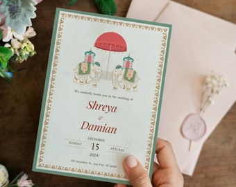 Puede incluir: Una invitación de boda con un borde verde y detalles dorados. La invitación presenta una ilustración de dos elefantes que llevan un dosel rojo y dorado. El texto dice "We cordially invite you to the wedding of Shreya & Damian, Sunday, December 15, 2024, at 11 a.m., 123 Anywhere St., Any City, ST 12345."