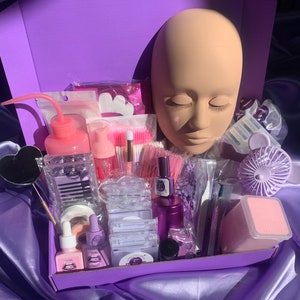 Könnte beinhalten: Eine violette Box gefüllt mit Wimpernverlängerungszubehör. Die Box enthält einen Wimpern-Übungskopf, Pinzetten, Wimpernkleber, Wimpernapplikatoren, Wimpernfächer und anderes Zubehör für Wimpernverlängerungen.