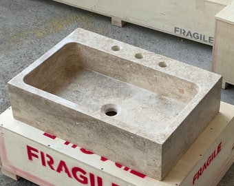 May include: A rectangular stone sink with a drain hole and three holes for fixtures. The sink is sitting on a wooden crate labeled "FRAGILE".